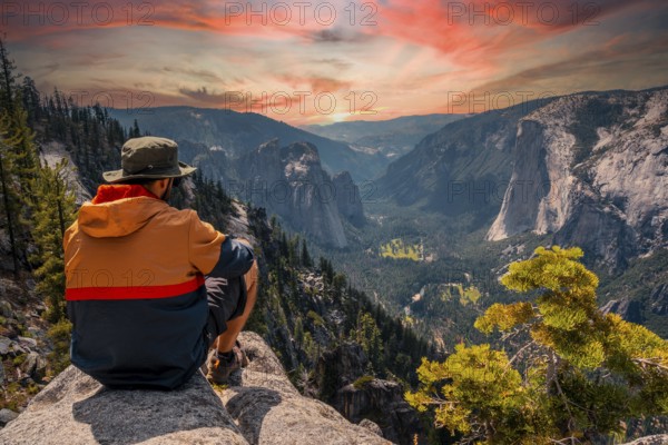 A young man on the trek sitting on the Sentinel Dome lookout in Yosemite National Park looking at El Capitan Mountain. United States