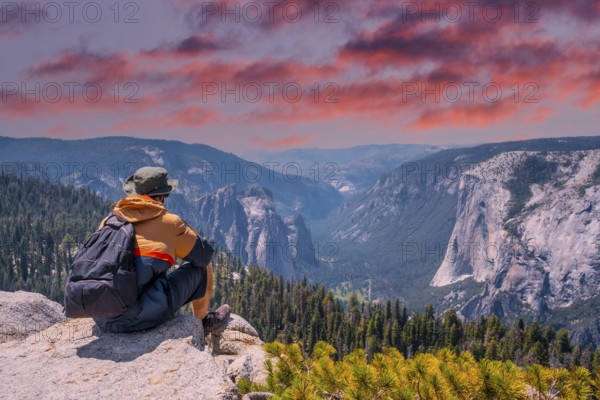 A young winged seated Taft point looking at Yosemite National Park and El Capitan in sunset. United States
