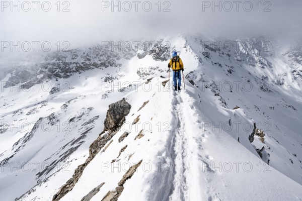 Mountaineer climbing up the narrow ridge of Piz Laviner, view of wintry mountain landscape, Grisons Haute Route, Albula Alps, Rhaetian Alps, Grisons, Eastern Switzerland, Switzerland, Europe
