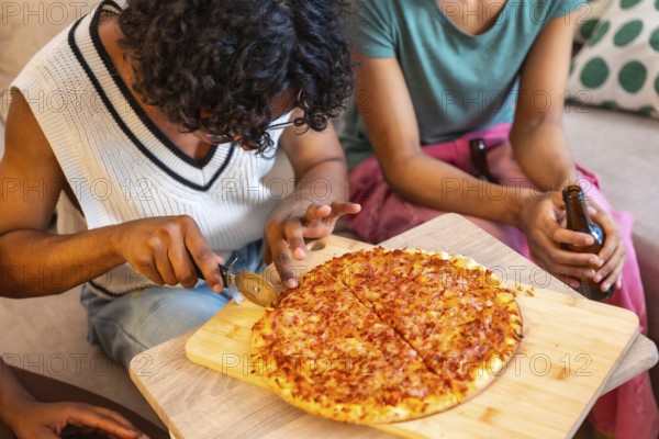 Close-up of man cutting homemade pizza to share with friends at home