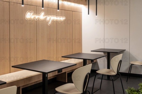 Empty tables and chairs illuminated by modern light fixtures create a workspace in an airport lounge