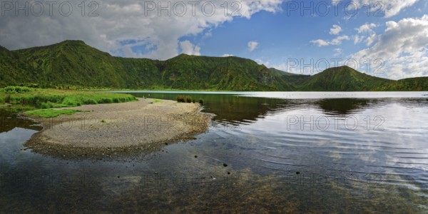 Calm lake surrounded by green mountains under a partly cloudy sky, crater lake Lagoa do Fogo, Caldeiras, Sao Miguel Island, Azores, Portugal, Europe