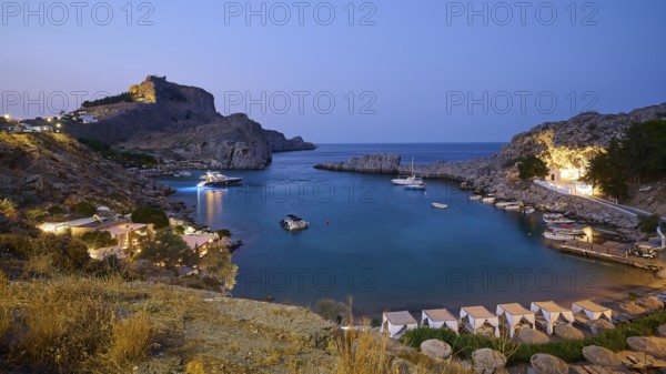 St Paul's Bay in the evening light, view of an illuminated bay with boats and calm water at dusk, Acropolis of Lindos, Lindos, Rhodes, Dodecanese, Greek Islands, Greece, Europe