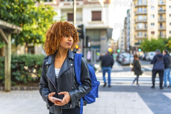Latin young woman carrying bag in the city holding phone and looking at directions