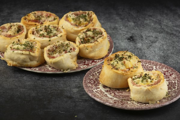Freshly baked sausage and cheese snails on decorative plates