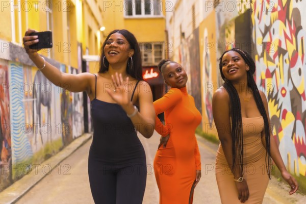 San Sebastián, Gipuzkoa Spain, February 2021: Three girls taking a selfie. Fashionable urban style with three black African girls on a city street, tight dresses