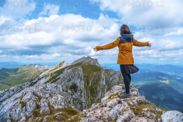 Mount Aizkorri 1523 meters, the highest in Guipúzcoa. Basque Country. Ascent through San Adrián and return through the Oltza fields. A young woman in yellow looking at the views on top