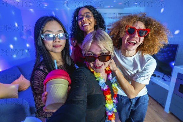 Four diverse friends enjoying a home disco party, taking a selfie with colorful lights, drinks, and festive accessories