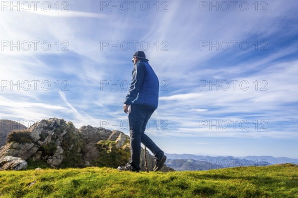 Male hiker using a walking stick while enjoying a sunny day on the summit of mount penas de aya or aiako harria, in oiartzun, basque country, spain
