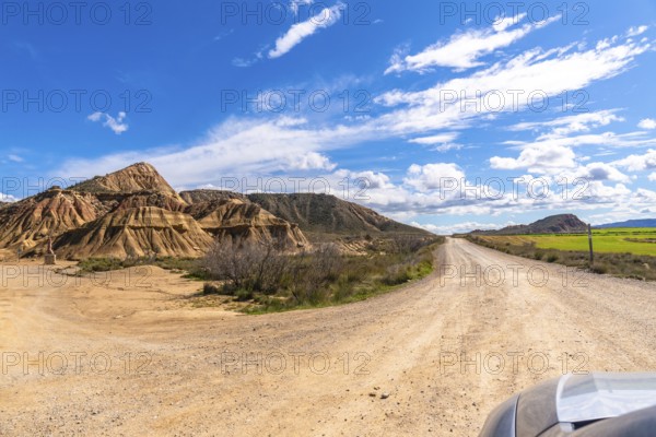Scenic view of a dirt road winding through the geological formations of bardenas reales desert in navarre, spain, under a bright blue sky