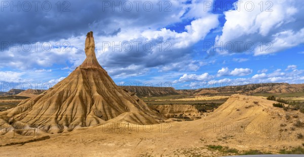Majestic castildetierra rock formation standing tall in the bardenas reales desert, navarre, spain, under a vibrant blue sky with dramatic clouds