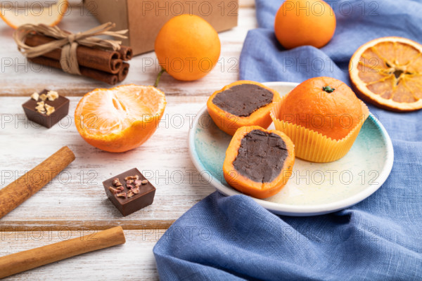 Truffle chocolate tangerine candies on a white wooden background and blue linen textile. Side view, close up