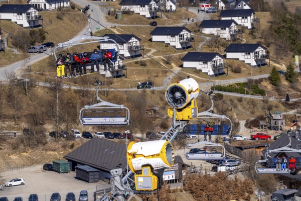 Winter sports area in the Sauerland, Winterberg ski lift carousel, artificial snow slopes, artificial snow from over 360 snow guns, Poppenberg ski area, background holiday homes at Landal Ferienpark Winterberg, 12 of 24 lifts are in operation in mid-March, the rest of the landscape is snow-free, North Rhine-Westphalia, Germany, Europe