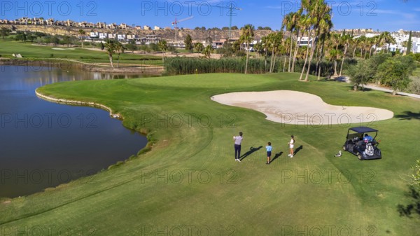 Aerial drone wide view of three people playing in a luxury golf course in summer