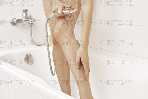 Unrecognizable woman washes the foam off her feet in the shower