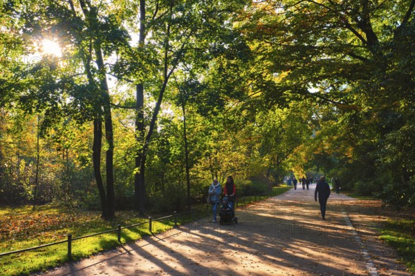 Munchen, Germany, October 21, 2019: Golden autumn fall October in famous Munich relax place, Englisher garten with pedestrians with fallen leaves and golden sunlight, Europe