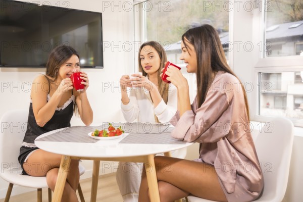 Lifestyle of Caucasian friends on vacation in a hotel having breakfast, dressed in nightwear and drinking coffee
