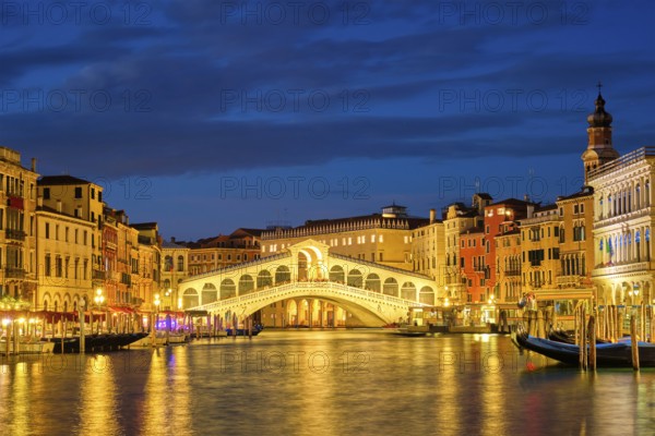 Famous Venetian tourist landmark Rialto bridge (Ponte di Rialto) over Grand Canal illuminated at night in Venice, Italy, Europe