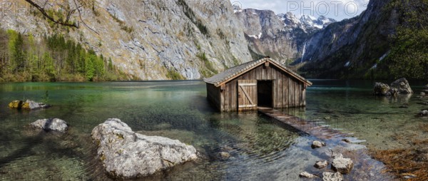 Panorama of Obersee mountain lake with boat dock hangar in Alps. Bavaria, Germany, Europe