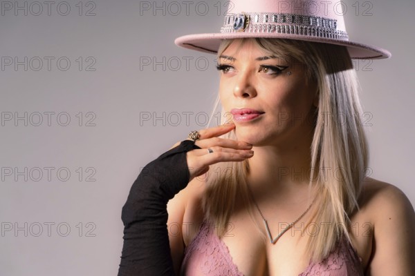 Attractive young blonde woman with long hair, wearing a pink cowboy hat and a pink bra, accessorized with black gloves and jewelry