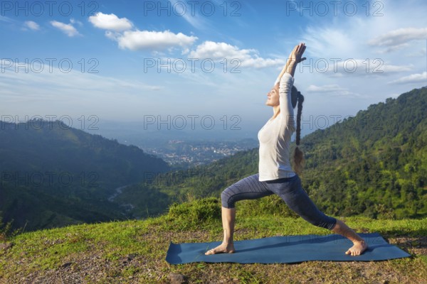 Yoga outdoors, sporty fit woman doing yoga asana Virabhadrasana 1, Warrior pose posture outdoors in Himalayas mountains in the morning
