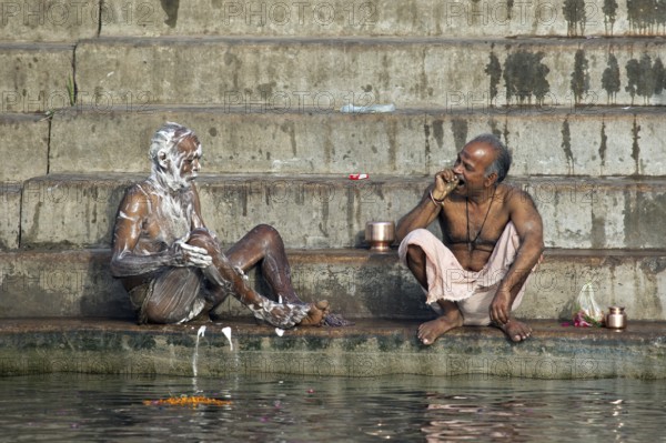 Indian men washing with soap and cleaning teeth at a ghat along the holy Ganges river, Varanasi, Uttar Pradesh, India, Asia