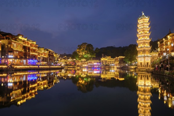 Chinese tourist attraction destination, Feng Huang Ancient Town (Phoenix Ancient Town) on Tuo Jiang River with Wanming Pagoda illuminated at night. Hunan Province, China, Asia