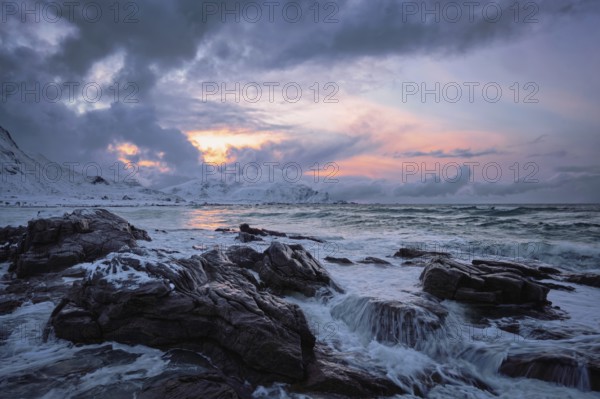Waves of Norwegian sea on rocky coast in fjord on sunset. Skagsanden beach, Lofoten islands, Norway, Europe