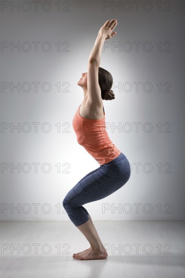 Sporty fit woman doing Surya Namaskar ashtanga vinyasa yoga asana Utkatasana, chair pose