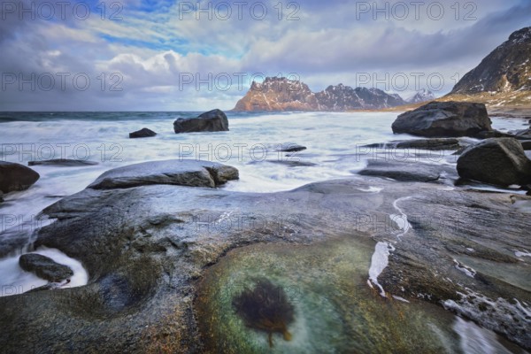 Rocks on beach of fjord of Norwegian sea in winter with snow. Utakliev beach, Lofoten islands, Norway, Europe