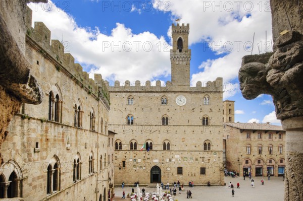 View of historical building from the Middle Ages Palazzo dei Priori town hall of Volterra built in 1208, 13th century, right foreground old symbolic figure on house corner, Volterra, Tuscany, Italy, Europe