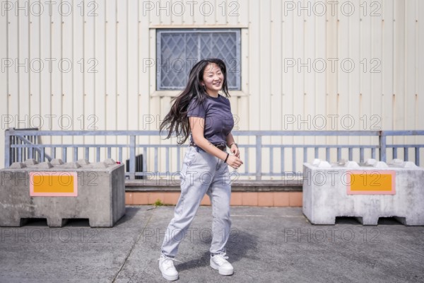 Happy asian young woman dancing k-pop alone in the city
