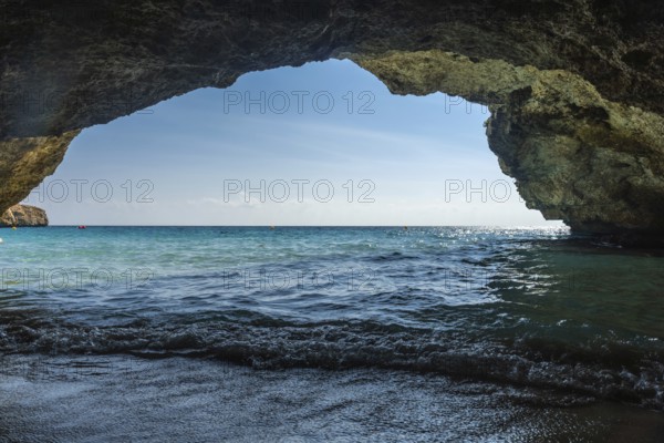 Breathtaking turquoise waves lapping the shore from inside a cave in cala domingos, mallorca, reveal a stunning mediterranean view