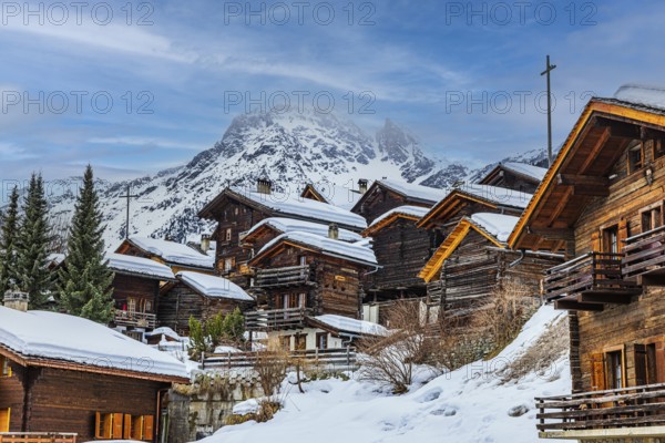 Old snow-covered wooden houses in the historic village centre, with the snow-covered summit of the Scex Marenda mountain in the background, Grimentz, Val d'Anniviers, Valais Alps, Canton Valais, Switzerland, Europe