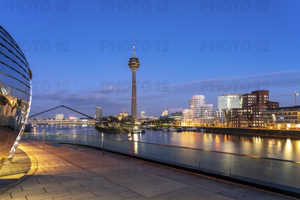 View from the terrace of the Hyatt Hotel of the Gehry buildings - Neuer Zollhof at the Media Harbour and the Rhine Tower in Düsseldorf at dusk, North Rhine-Westphalia, Germany, Europe