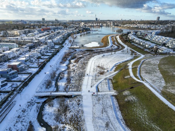Dortmund, North Rhine-Westphalia, Germany, Phoenix Lake in winter with snow, renaturalised Emscher in front. The river was transformed into a near-natural body of water, flood protection and biodiversity through newly designed floodplains. A former industrial wasteland of 99 hectares was transformed into residential, work and leisure areas and 24 hectares of lake surface. In the event of heavy rainfall, the lake acts as a rainwater retention basin. Following the construction of a parallel sewer, the Emscher is now free of wastewater, having previously been an open, above-ground wastewater sewer, combined sewer with surface water and wastewater. The Phoenix Lake, a showcase project for structural change, is an artificial lake on the site of the former Phönix Ost steelworks in Dortmund's Hörde district, Europe