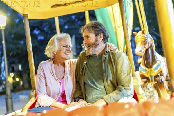 Happy senior friends sitting together in an old fashion carousel illuminated by light at night in the city