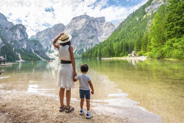 Mother and son enjoying summer vacation at lake braies, surrounded by stunning mountain scenery in the dolomites, italy