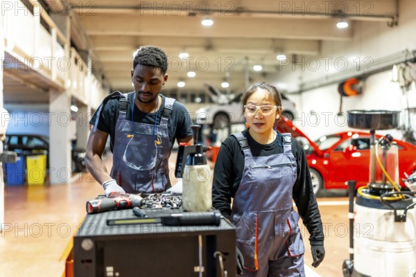 Two auto mechanics are performing maintenance in a professional car workshop, showcasing teamwork and expertise in automotive repair