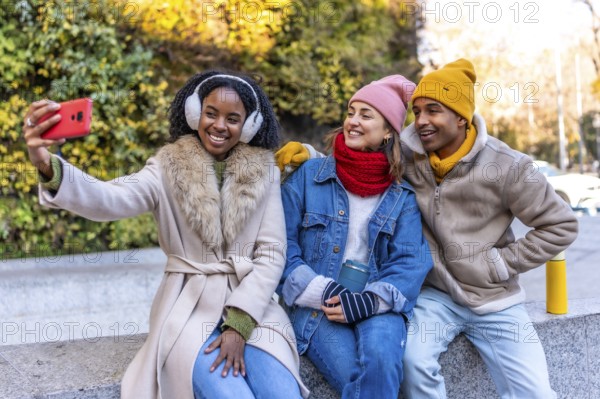 Three friends are taking a selfie in the city during winter, enjoying their time together
