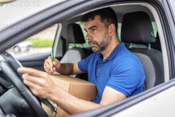 Delivery man checking a package ready to deliver sitting inside a car