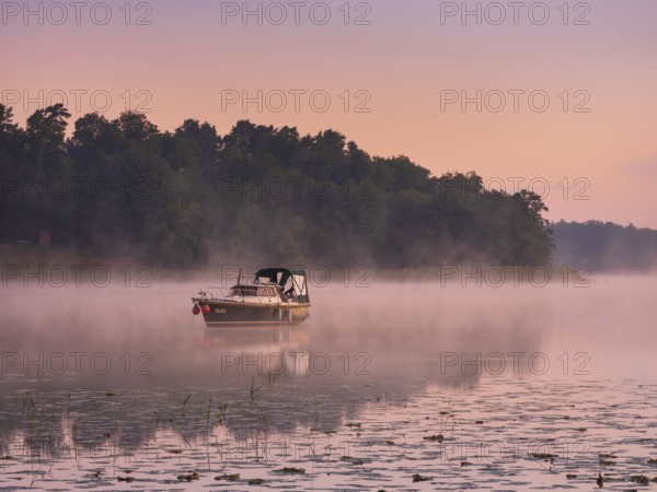 Morning atmosphere at Lake Grienerick, boat anchored, morning mist on the water, Rheinsberg, Brandenburg, Germany, Europe