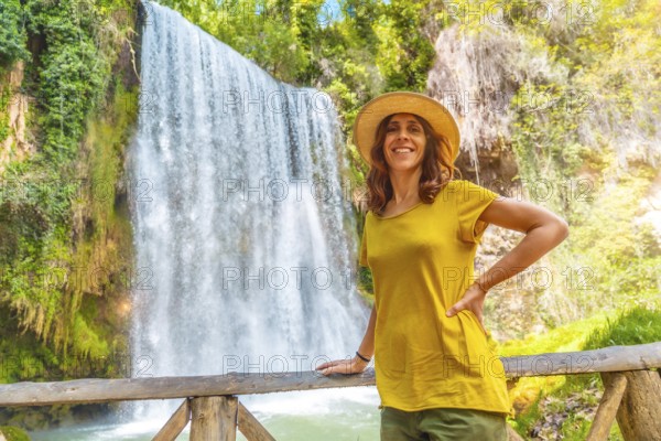 Portrait of a female tourist with a hat looking at La Caprichosa waterfall in the Monasterio de Piedra Natural Park, Aragon, Spain, Europe