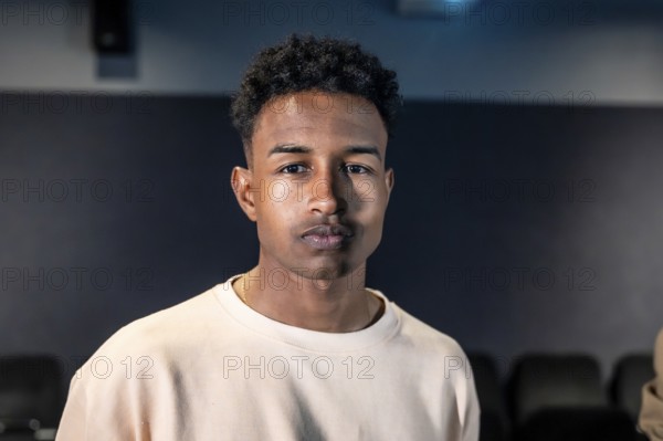 Portrait of a young man standing in a movie theater during a movie session, possibly participating in a movie disco dance or a special event