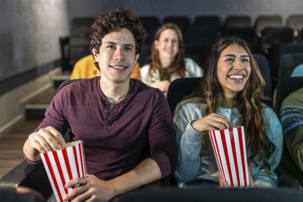 Happy couple enjoying a movie night at the cinema, sharing popcorn and smiles while immersed in the excitement of the big screen