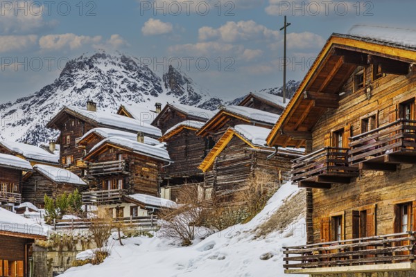 Old snow-covered wooden houses in the historic village centre, with the snow-covered summit of the Scex Marenda mountain in the background, Grimentz, Val d'Anniviers, Valais Alps, Canton Valais, Switzerland, Europe