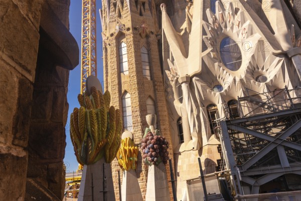 Colorful ceramic pinnacles and construction crane are visible at sagrada familia in barcelona, a unesco world heritage site