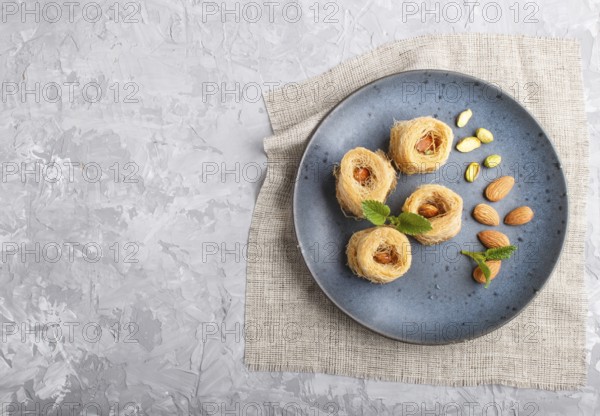 Kunafa, traditional arabic sweets in blue ceramic plate on a gray concrete background. top view, copy space