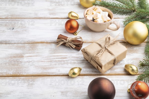 Christmas or New Year composition. Decorations, box, golden balls, cinnamon, fir and spruce branches, cup of coffee, on a white wooden background. Side view, copy space