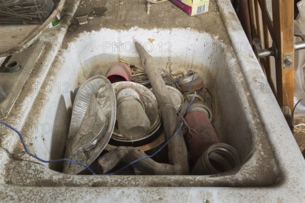 Unwashed dishes and other objects in dirty white sink inside an old barn, Quebec, Canada, North America